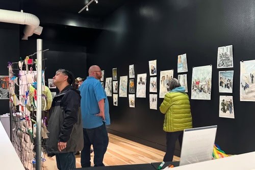 Visitors looking at Sam Marroquin's artwork in Seeking Warmth, photo by Sharon Svec.