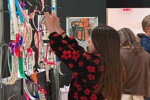 A young visitor ties a message onto the interactive installation artwork, photo by Sharon Svec.  