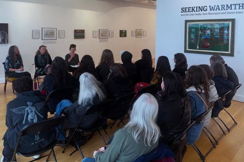 People seated in the gallery for an artist talk for the exhibit Seeking Warmth.