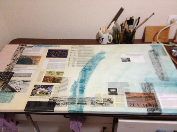 Adding magazine clippings to this collage painting sitting on a work table.