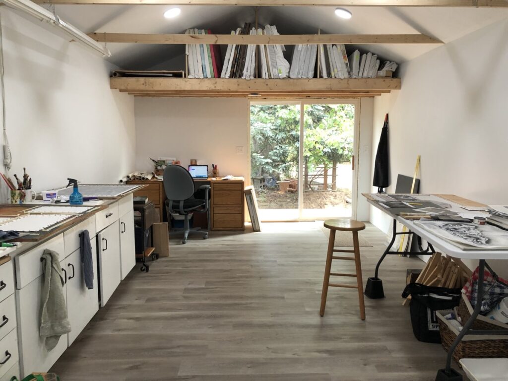 large art studio with desk, work tables, storage cabinets and sliding glass door