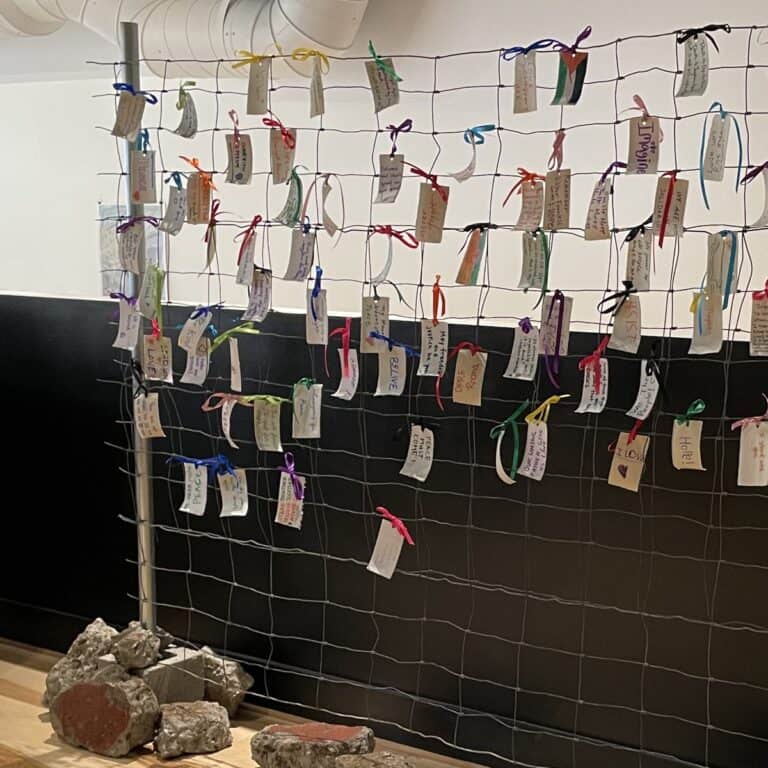 Messages of hope and resistance written on torn canvas and tied to a wire fence held up by broken concrete rubble as apart of an interactive art installation.
