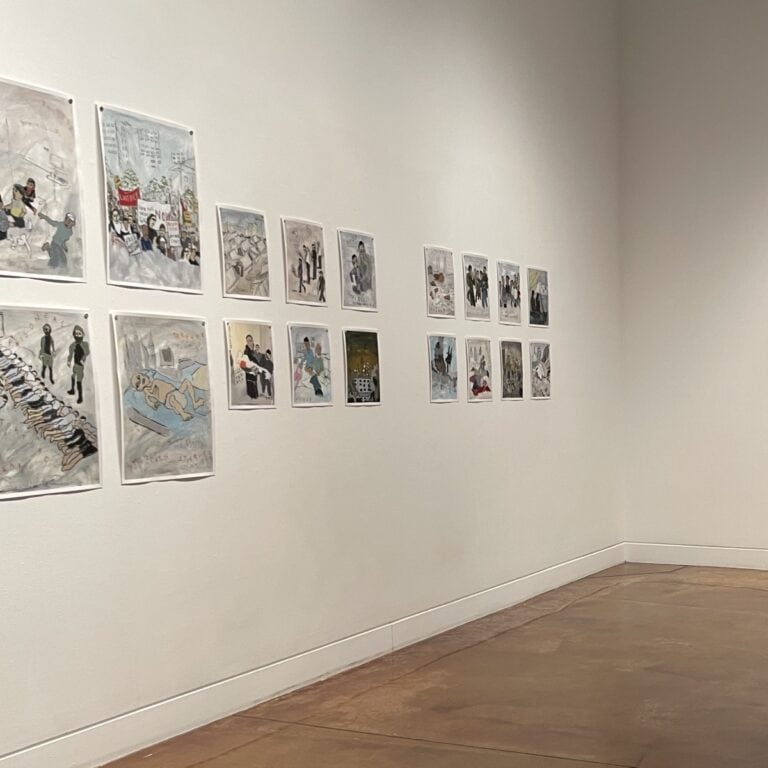 Artwork hanging on a white wall in a gallery.